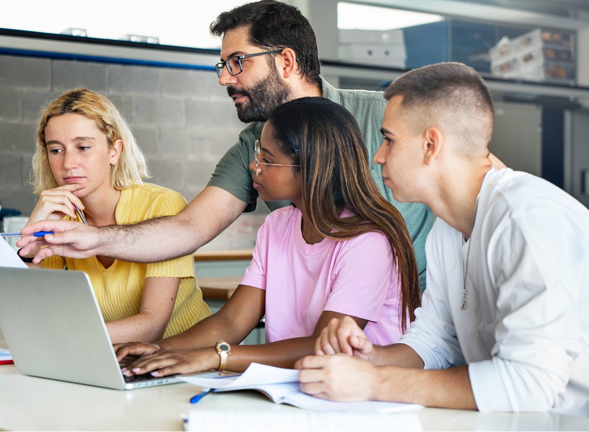 Students working with a teach in class on one computer