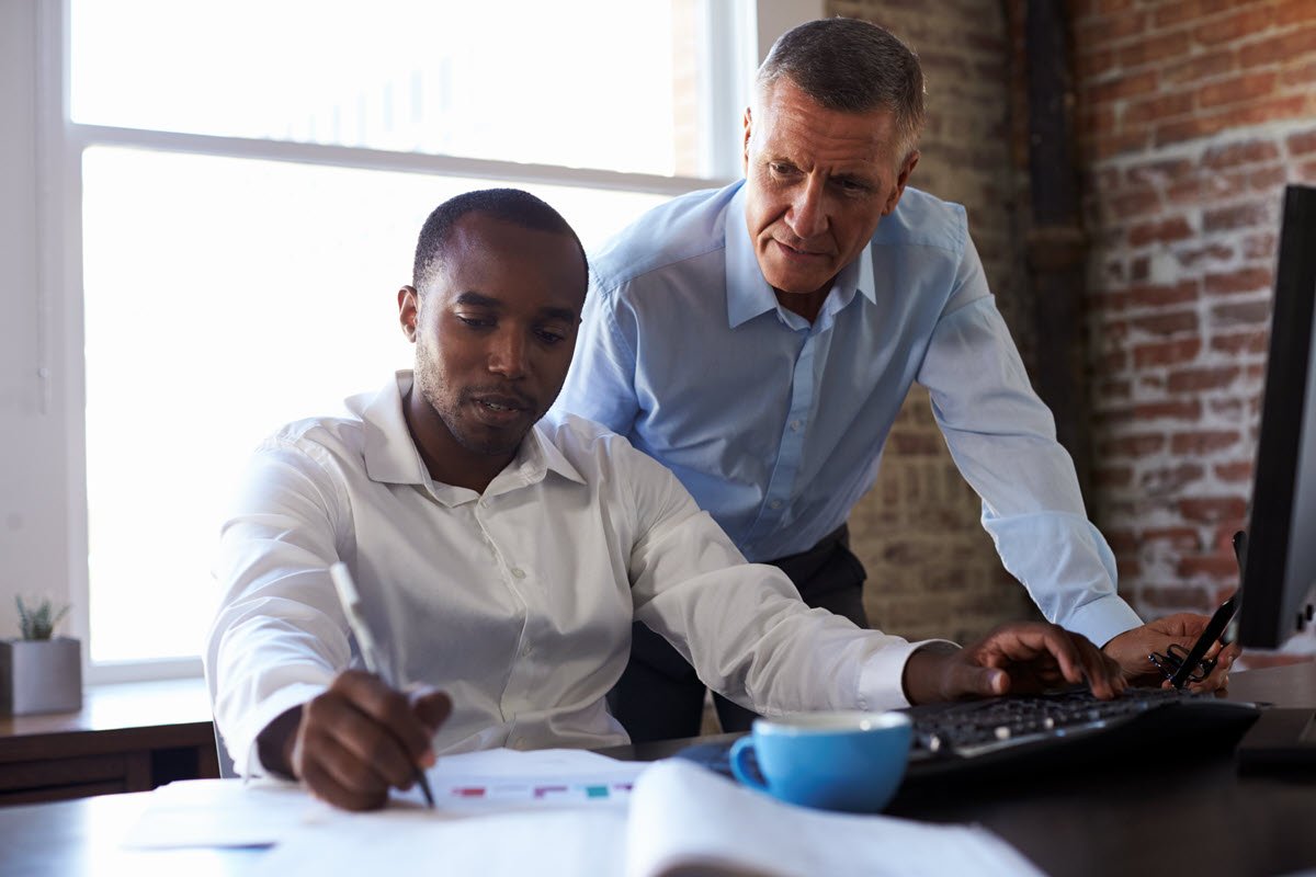 Two men work at computer together